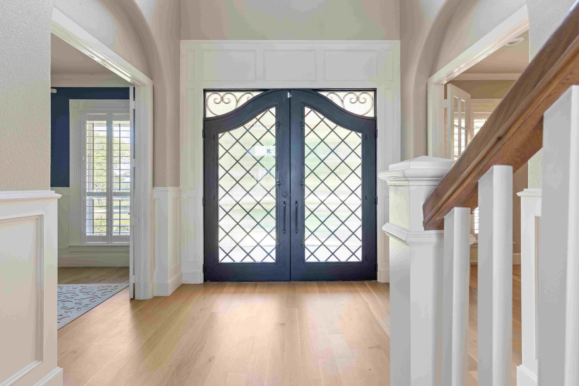 Two-story foyer with wrought iron double doors and hardwood floors