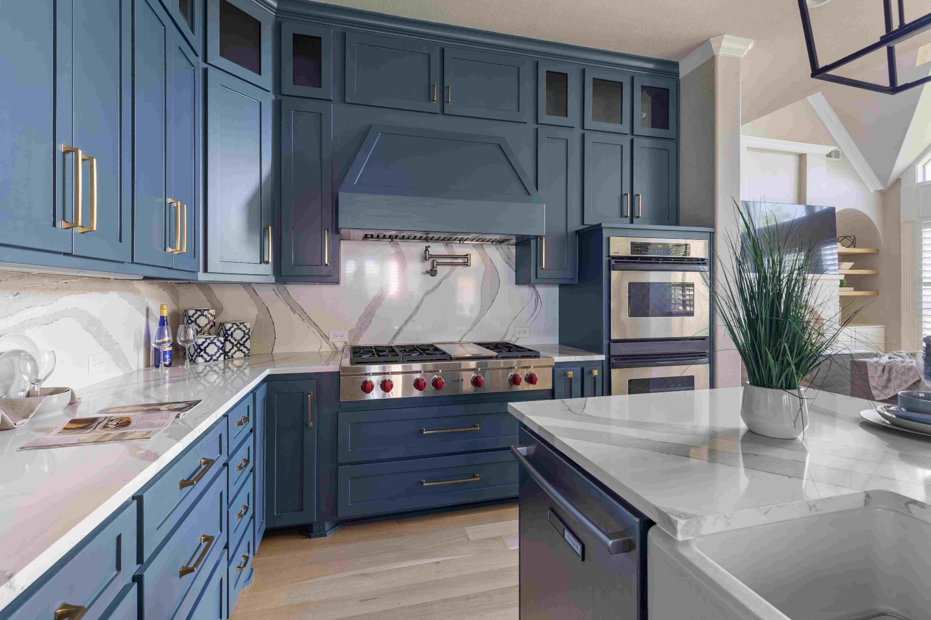 Kitchen with Wolf gas range, navy cabinetry, brass hardware, and marble backsplash