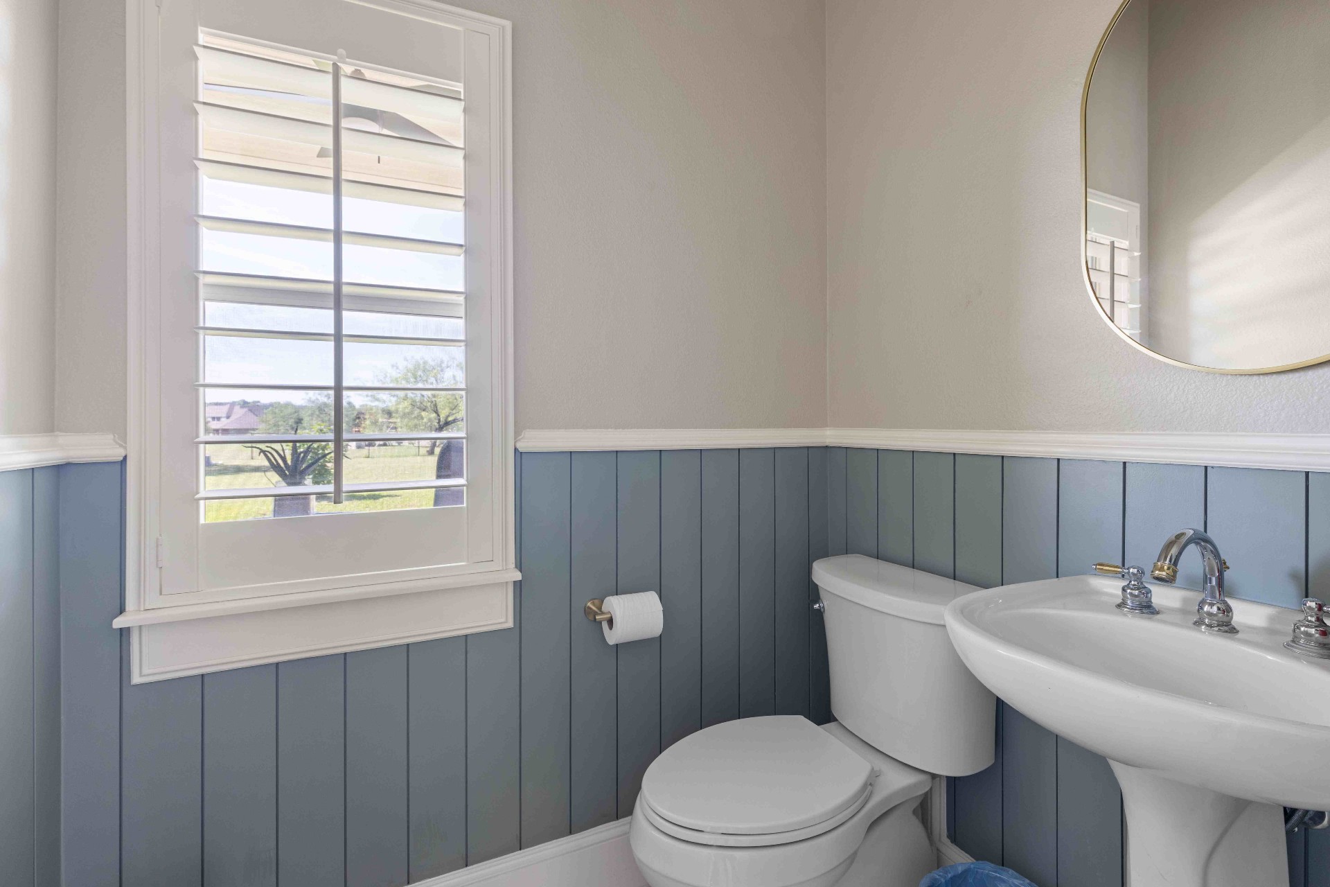 Powder room with blue shiplap wainscoting, pedestal sink, and pasture view