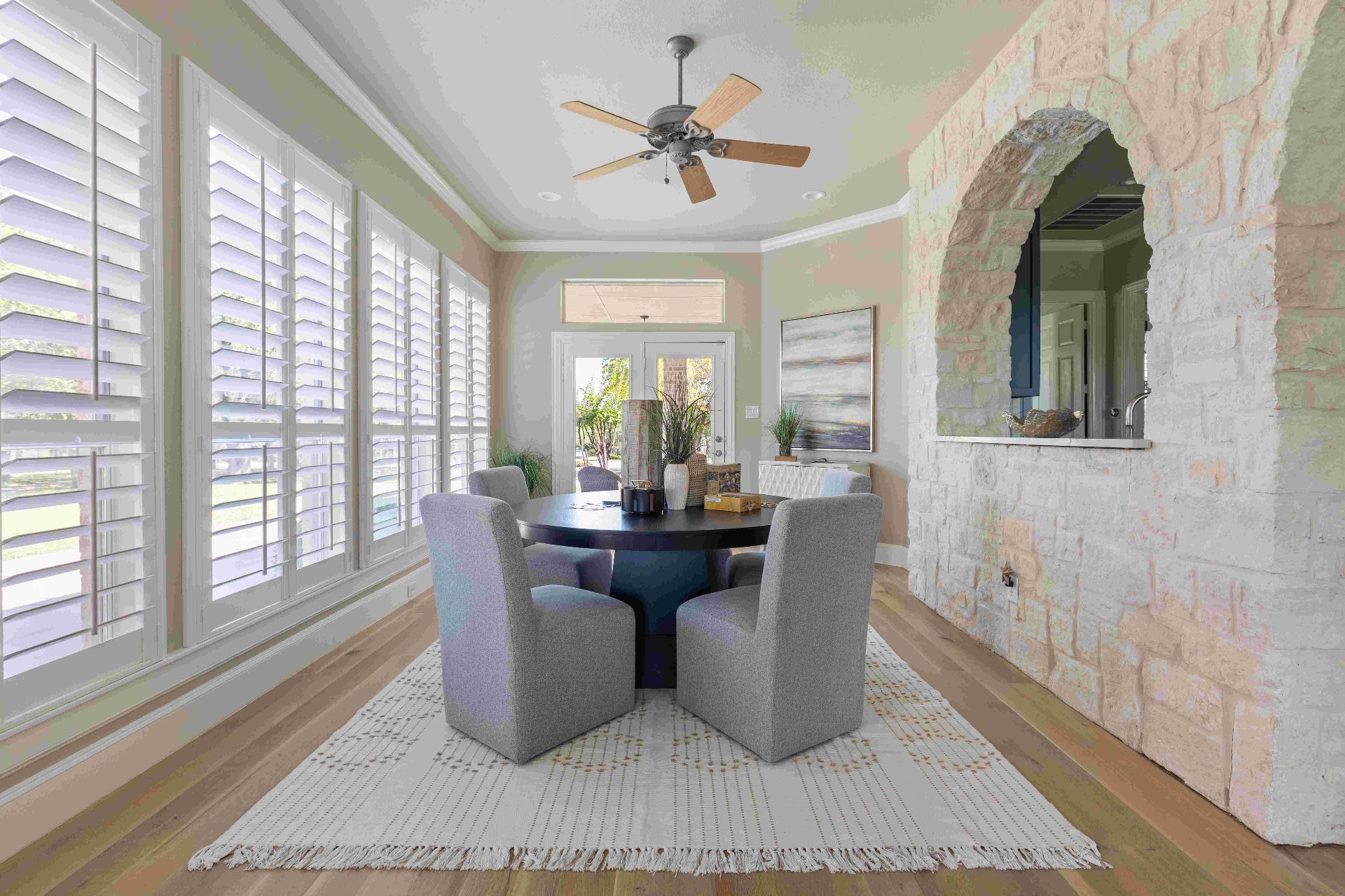 Breakfast nook with stone archway, plantation shutters, and patio access