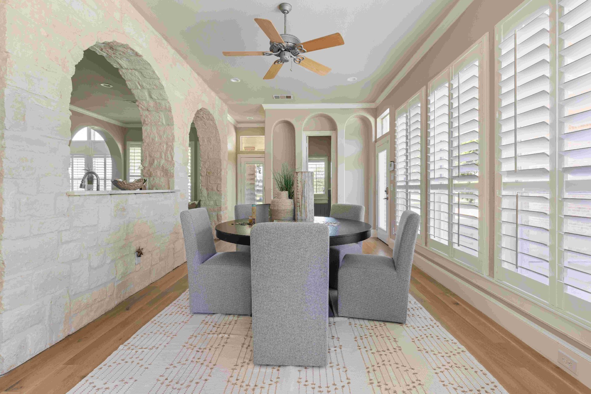 Sunroom breakfast nook with stone archways and wraparound shutters