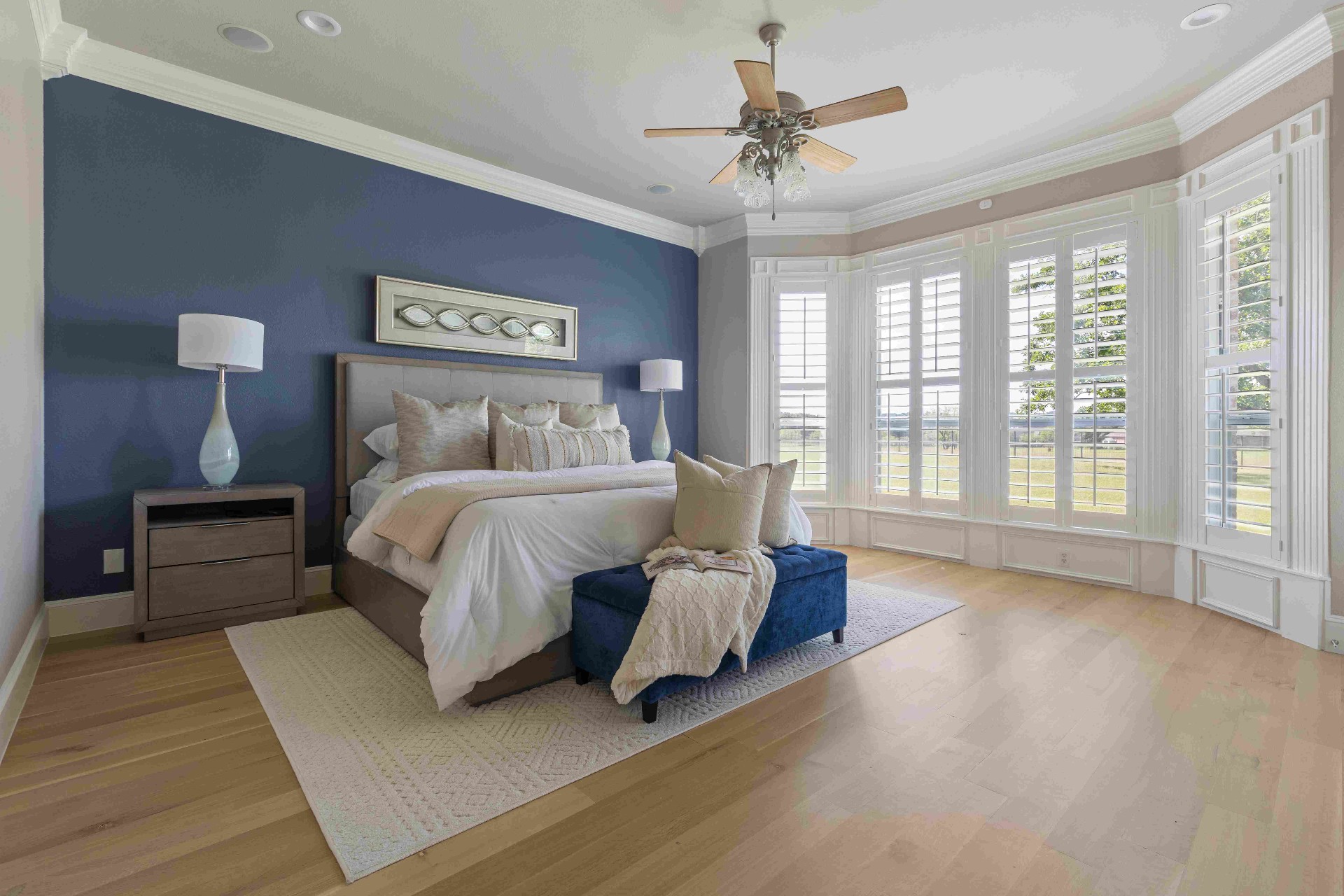 Primary bedroom with navy accent wall, bay windows, and pasture views