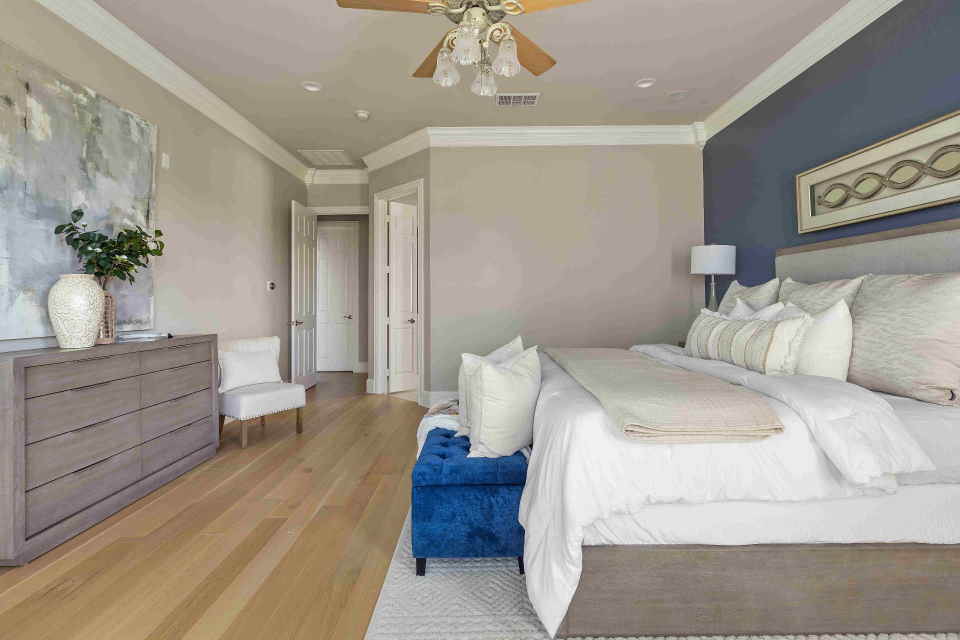 Primary bedroom with navy accent wall, king bed, and hardwood floors