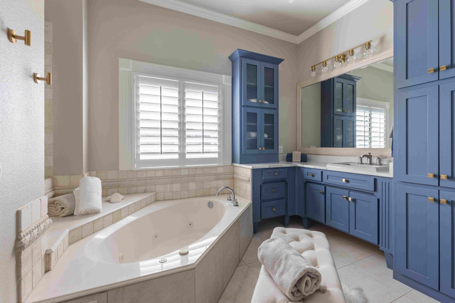 Primary bath with jetted soaking tub, navy cabinetry, and brass fixtures