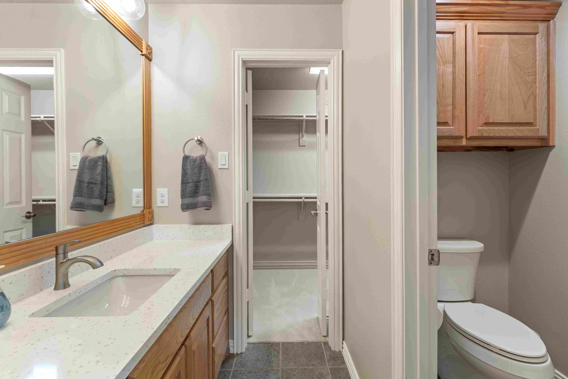 Secondary bath with oak cabinetry, quartz vanity, and walk-in closet